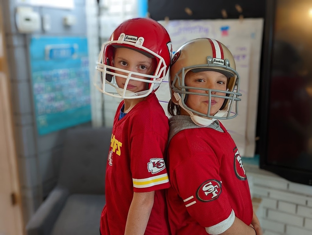  Two students standing back to back dressed as football players
