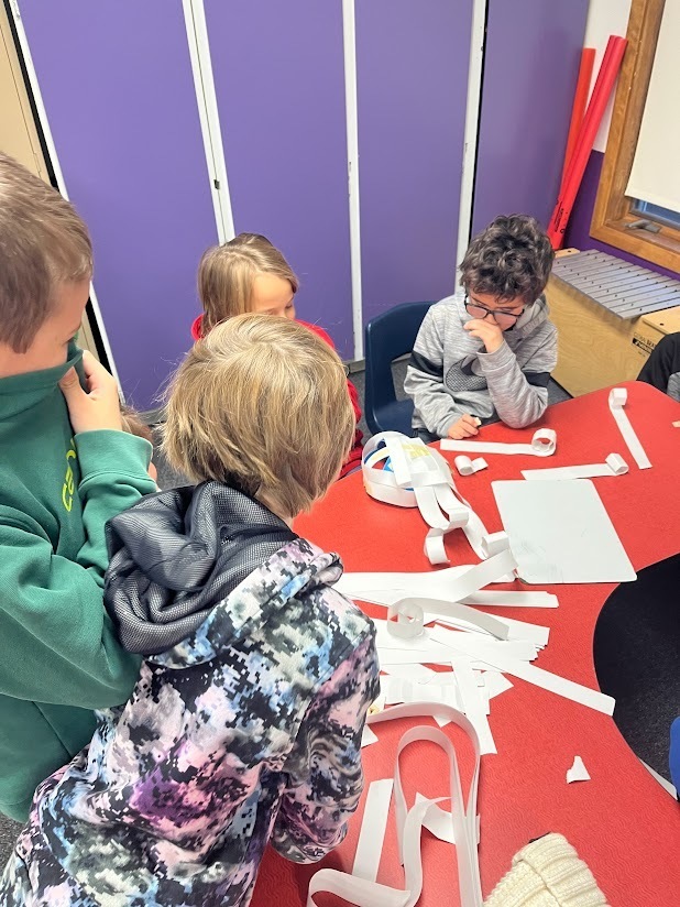  Group of students gathered around table with cut paper